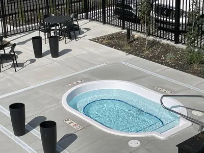 a jacuzzi tub on a patio with a table and chairs at Skyline Soak - Pool & Hot Tub & Mountain Views in Canmore