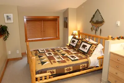 a bedroom with a bed with a wooden frame at Apartment 405 Bear Creek Crossing in Canmore