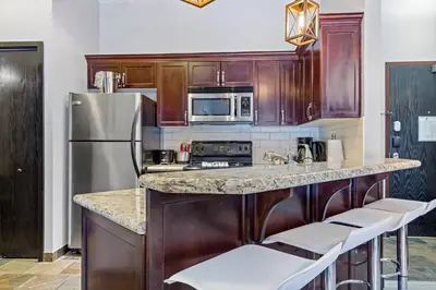 a kitchen with wooden cabinets and a stainless steel refrigerator at Nature's Nook by Instant Suites Pool & HotTub in Canmore