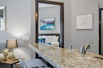 a living room with a large marble counter and a bedroom at Nature's Nook by Instant Suites Pool & HotTub in Canmore