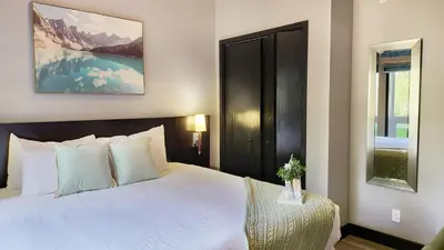 a bedroom with a large white bed and a window at Nature's Nook by Instant Suites Pool & HotTub in Canmore