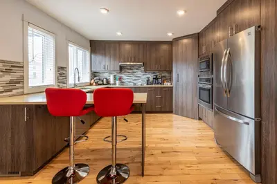 a kitchen with wooden cabinets and a stainless steel refrigerator at Mountain View Escape with Private Hot Tub & Patio in Canmore