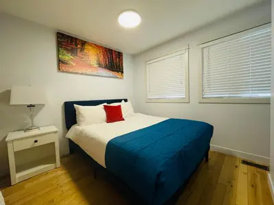 a bedroom with a bed with a blue blanket and two windows at Mountain View Escape with Private Hot Tub & Patio in Canmore