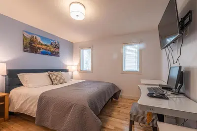 a bedroom with a bed and a desk with a computer at Mountain View Escape with Private Hot Tub & Patio in Canmore