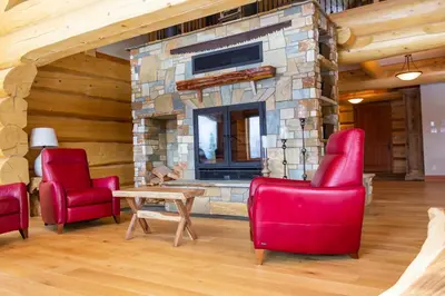 a living room with red chairs and a stone fireplace at Jollymore Ranch in Smithers