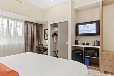 a hotel room with a bed and a tv at Mountain View Inn & Suites in Sundre