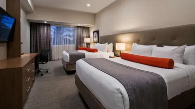 a hotel room with two beds and a flat screen tv at Mountain View Inn & Suites in Sundre