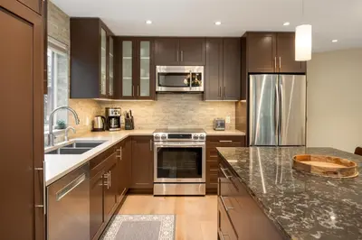 a kitchen with wooden cabinets and stainless steel appliances at 3BR in Snowgoose, Ski In, Luxury Property, Free Shuttle to Lifts, Parking in Whistler