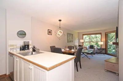a kitchen with a sink and a living room at Aspens on the Mountain Ski In Out in Whistler