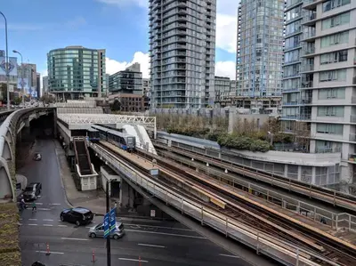 a train on a track in a city with buildings at Beautiful 1 BR in the Heart of Downtown: Parking, Pool & Gym in Vancouver