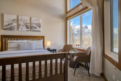 a bedroom with a bed and a window with mountains at Incredible Mountain View Townhouse in DT Canmore w/ A/C & U/A Parking in Canmore