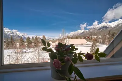 a vase of flowers sitting in a window with a view at Incredible Mountain View Townhouse in DT Canmore w/ A/C & U/A Parking in Canmore