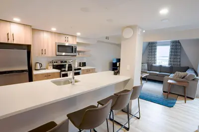a kitchen and living room with a counter and chairs at Basecamp Suites Banff in Banff