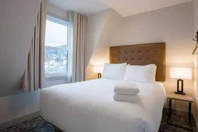 a bedroom with a large white bed with a window at Basecamp Suites Banff in Banff