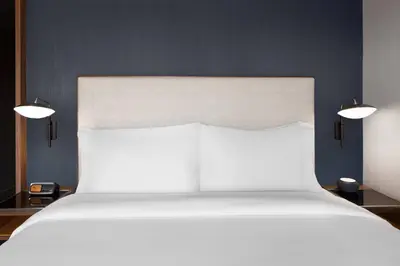 a large white bed with two lights above it at Courtyard by Marriott Calgary Downtown in Calgary