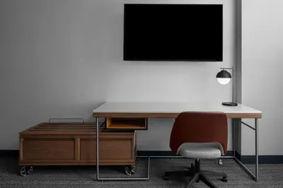 a desk with a chair and a tv on a wall at Courtyard by Marriott Calgary Downtown in Calgary