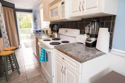 a kitchen with white cabinets and a white stove top oven at Downtown Whitehorse Apartment in Old Town in Whitehorse