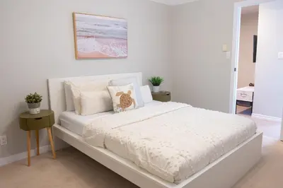 a white bedroom with a white bed with pillows at Harrison On The Lake, Walkable to Beach and Village in Harrison Hot Springs