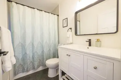 a bathroom with a sink and a toilet and a mirror at Storm Bay, Family Home with Hot Tub and Inlet View in Ucluelet