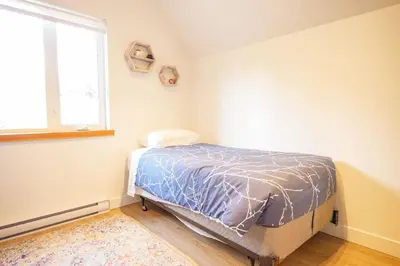 a bedroom with a bed in a room with a window at Storm Bay, Family Home with Hot Tub and Inlet View in Ucluelet