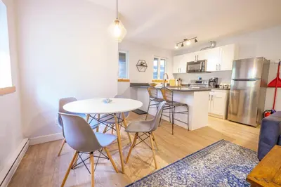 a kitchen and living room with a table and chairs at Storm Bay, Modern 1 Bed Suite and Chefs Kitchen in Ucluelet
