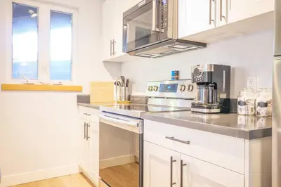 a kitchen with white cabinets and stainless steel appliances at Storm Bay, Modern 1 Bed Suite and Chefs Kitchen in Ucluelet