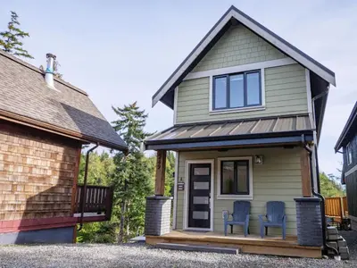 a tiny house with two chairs on the porch at Storm Bay, Modern 1 Bed Suite and Chefs Kitchen in Ucluelet