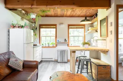 a kitchen with a refrigerator and a table in a room at Fern Gully, Coastal Bohemian Loft at Beach in Ucluelet