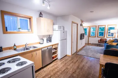 a kitchen with white appliances and a living room at Kingfisher, Waterfront Cabin with Inlet with Mountain Views in Ucluelet