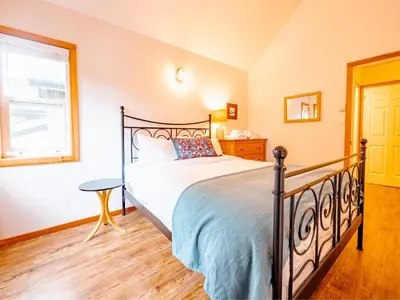 a bedroom with a bed and a window at Kingfisher, Waterfront Cabin with Inlet with Mountain Views in Ucluelet