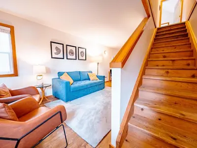 a living room with a staircase and a blue couch at Kingfisher, Waterfront Cabin with Inlet with Mountain Views in Ucluelet