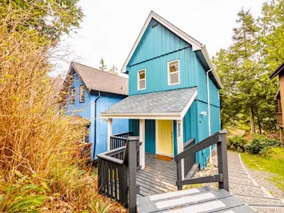 a blue house with a wooden boardwalk in front of it at Kingfisher, Waterfront Cabin with Inlet with Mountain Views in Ucluelet