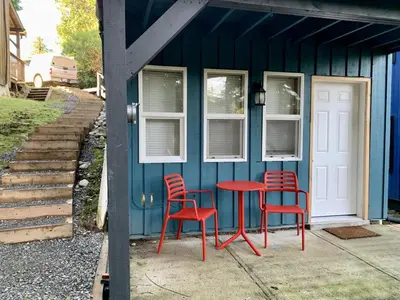 two red chairs and a red table in front of a blue house at Kingfisher, Newly Renovated Suite on Ocean Inlet in Ucluelet