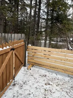 a wooden fence with snow on it next to a gate at Canmore Cabin by Canadian Rockies Vacation Rentals in Canmore