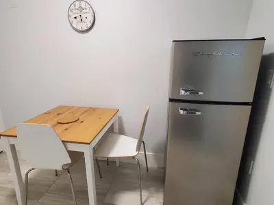 a kitchen with a refrigerator and a table and a clock at Cozy Guest Suite in Quiet Home with Private Entry in Vancouver