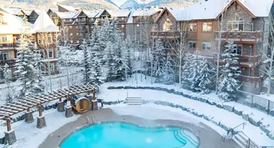 a resort with a pool in the snow at Spacious Penthouse Suite-King Beds-Pool & Hot Tub in Canmore