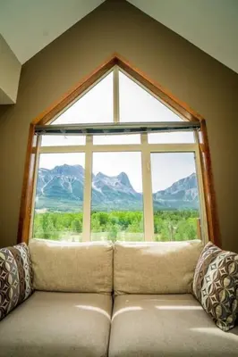 a couch sitting in front of a large window at Spacious Penthouse Suite-King Beds-Pool & Hot Tub in Canmore