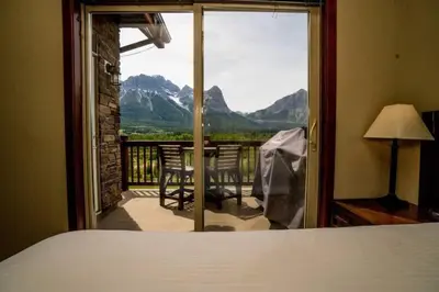 a bedroom with a bed and a view of a balcony at Spacious Penthouse Suite-King Beds-Pool & Hot Tub in Canmore