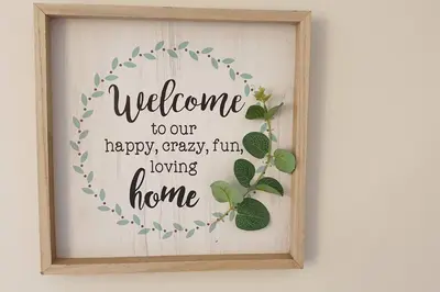 a welcome sign in a wooden frame with a welcome to our happy happy crazy fun at Happy, Cozy, Loving Guest Space in West Vancouver in West Vancouver