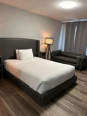 a bedroom with a large bed and a couch at Parkside Inn in Grande Prairie