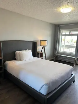 a bedroom with a large white bed with a window at Parkside Inn in Grande Prairie