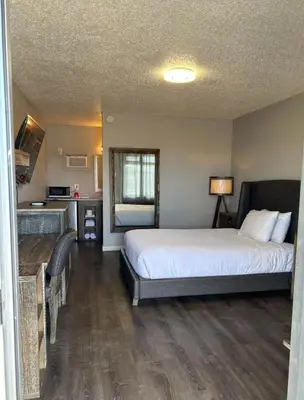a bedroom with a large bed and a kitchen at Parkside Inn in Grande Prairie