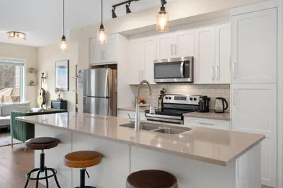a kitchen with white cabinets and a stainless steel refrigerator at Casa de Luna by Canadian Rockies Vacation Rentals in Canmore