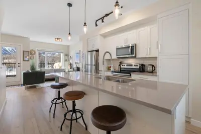 a kitchen with white cabinets and a large island with bar stools at Casa de Luna by Canadian Rockies Vacation Rentals in Canmore