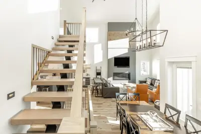 a staircase in a living room with a table and a dining room at The White Pearl - Amazing Luxury Chalet with Mountain Views in Big White