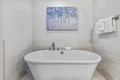 a white bath tub in a bathroom with a painting at BRAND NEW - Gorgeous Spring Creek Penthouse in Canmore