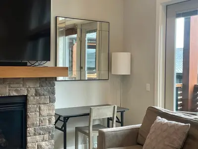 a living room with a couch and a table and a mirror at BRAND NEW - Gorgeous Spring Creek Penthouse in Canmore