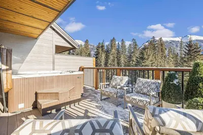 a patio with chairs and a hot tub on a deck at Spring Creek Vacations in Canmore