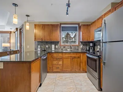 a kitchen with wooden cabinets and stainless steel appliances at Sunny Tranquil Woods Turret in Falcon Crest Lodge in Canmore