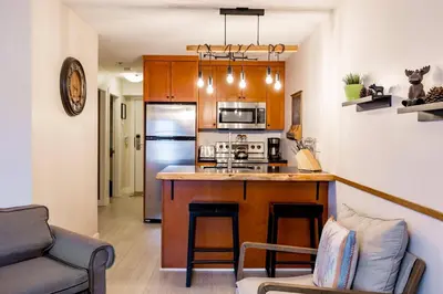 a kitchen with a counter and a stove top oven at 1BR plus Den in Marketplace Lodge, Village Location, Mountain Views, Complex Hot Tub in Whistler